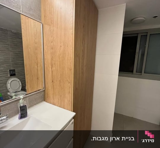 ארון עץ גבוה ליד כיור בחדר אמבטיה